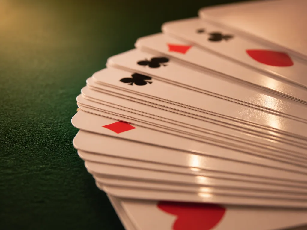 Plastkortlekar fläktat på grönt casinofilt, blank kortlek i plast i närbild